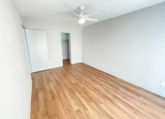 A room with a ceiling fan and wooden flooring.