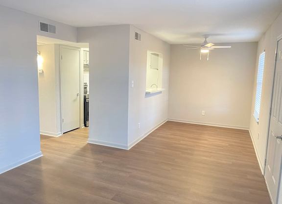 A room with a ceiling fan and light, and a doorway leading to another room.