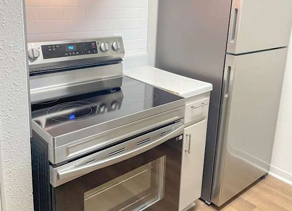 A modern kitchen with a stainless steel refrigerator and oven.