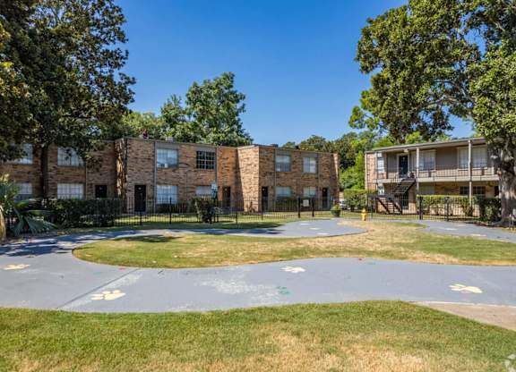 A playground area with a roundabout and a building in the background.