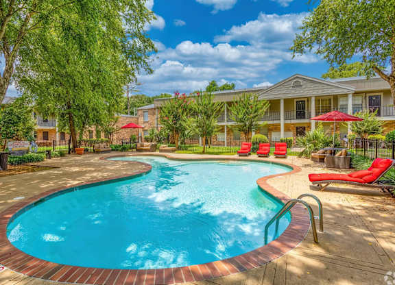 A swimming pool surrounded by a red brick border with a building in the background.