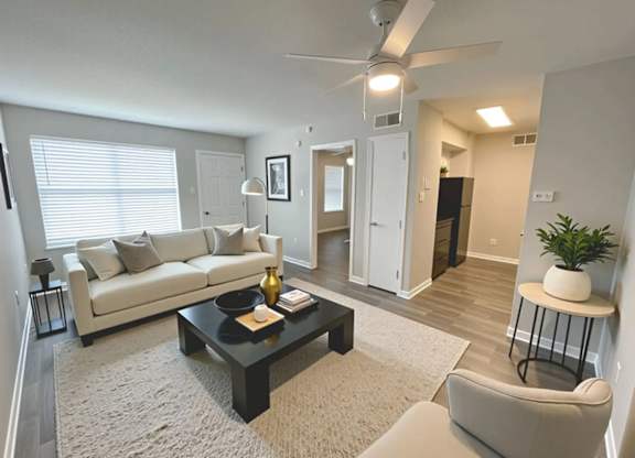 A living room with a white couch, a black coffee table, and a ceiling fan.