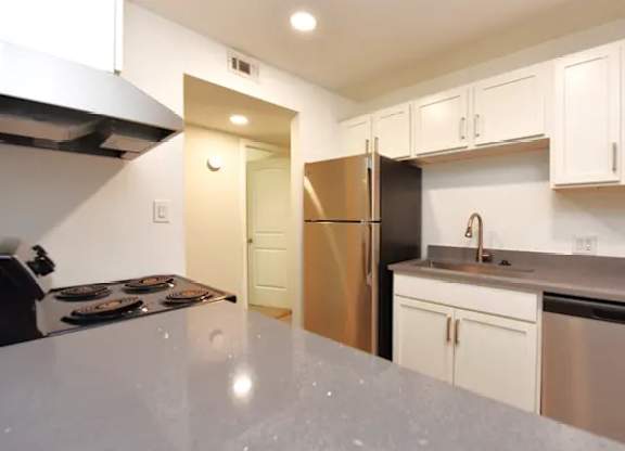 A kitchen with white cabinets and a stainless steel refrigerator.