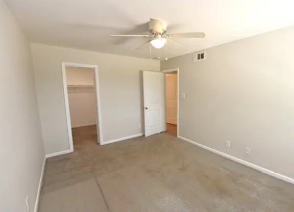 A room with a ceiling fan and a door.