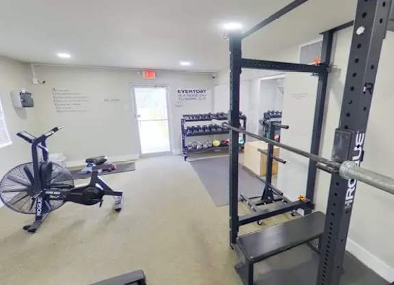 A gym with a rowing machine and weight racks.