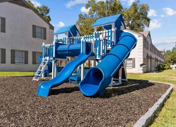 A blue playground slide in front of a building.