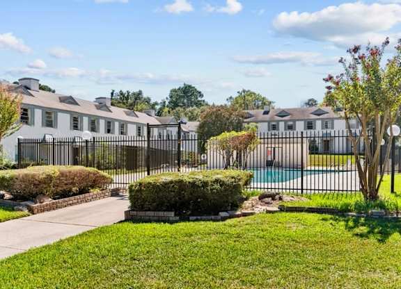 A row of houses with a fence and a pool in the foreground.