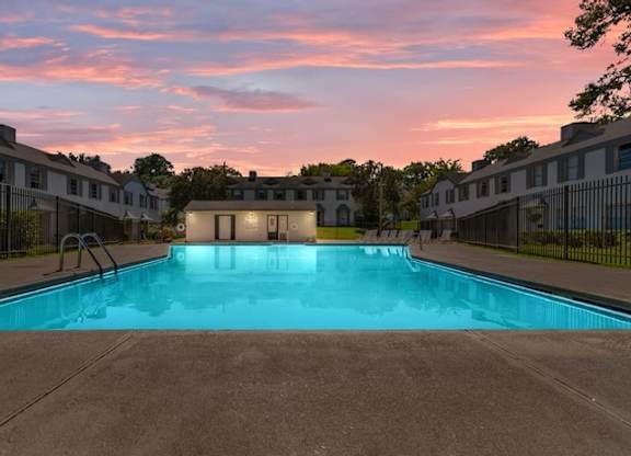 A swimming pool in front of a building with a sunset in the background.