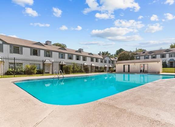 A swimming pool in front of a building with a fence around it.