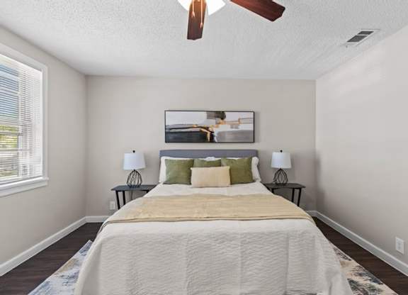 A bedroom with a bed, two lamps, and a painting on the wall.