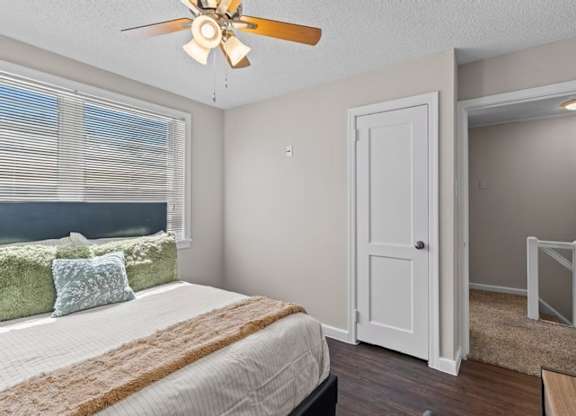 A bedroom with a bed, a ceiling fan, and a window with blinds.