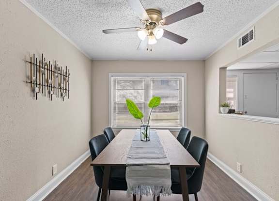 A dining room with a table, chairs, and a ceiling fan.