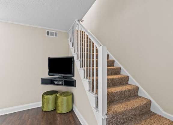 A staircase with a TV and stool.