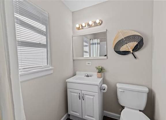 A white bathroom with a toilet, sink, and mirror.