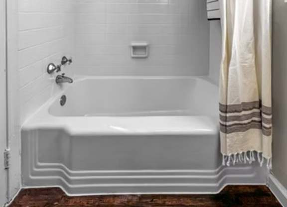 A white bathroom with a white tub and a white shower curtain.