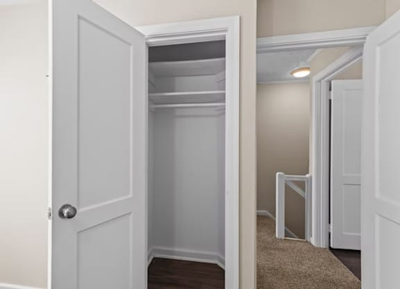 A white door is open to a small, empty closet.