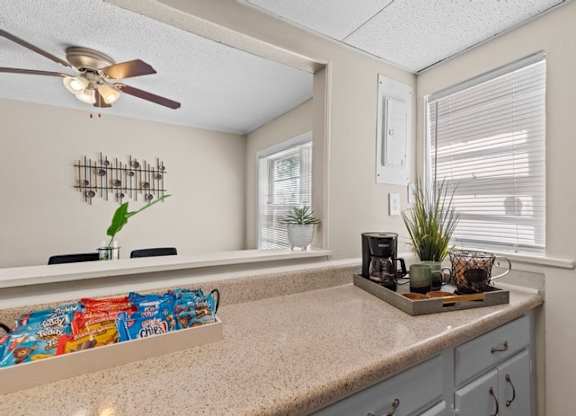 A kitchen with a counter, a fan, and a window.