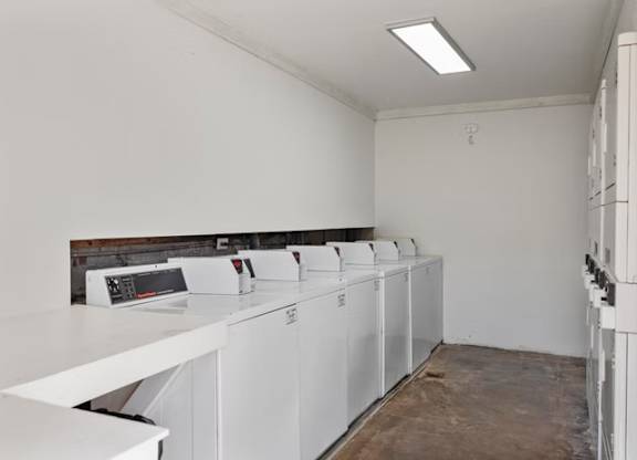 A row of washing machines are lined up in a laundry room.