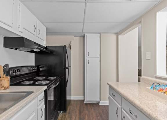 A kitchen with a black stove top oven and white cabinets.