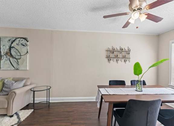 A living room with a couch, chairs, and a table with a plant on it.