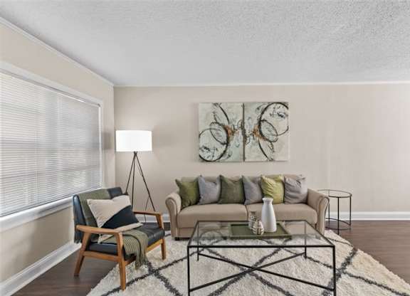 A living room with a couch, chair, and a painting on the wall.