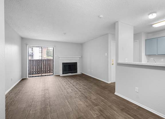 A spacious living room with a fireplace and wood flooring.