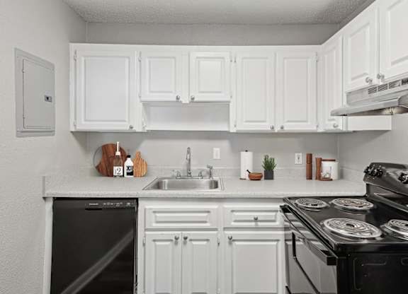 A white kitchen with black appliances and a black dishwasher.