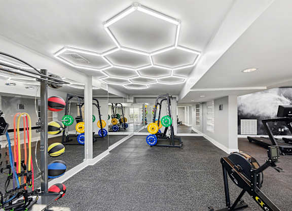 A gym with a variety of equipment including a rowing machine, a treadmill, and a stationary bike.