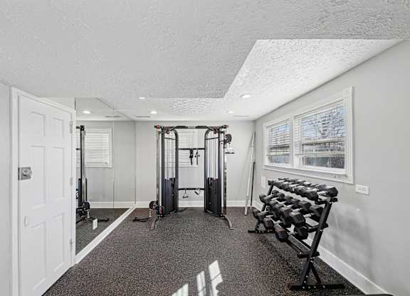 A home gym with a variety of equipment including a squat rack, bench, and dumbbells.
