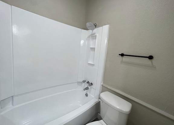 A white bathroom with a toilet, tub, and towel rack.