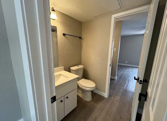 A bathroom with a toilet, sink, and mirror.