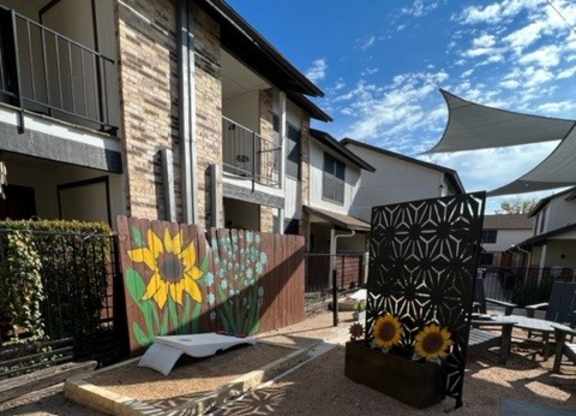 A sunflower mural is painted on a wall in front of a building.