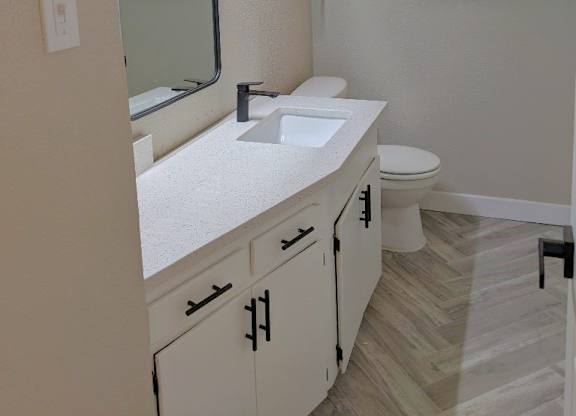 A bathroom with a sink, toilet, and mirror.