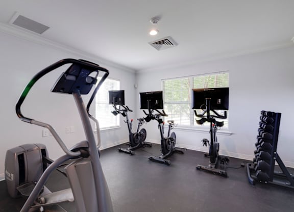 A gym with a treadmill, exercise bike, and weights at Retreat at Savannah Apartments, Savannah