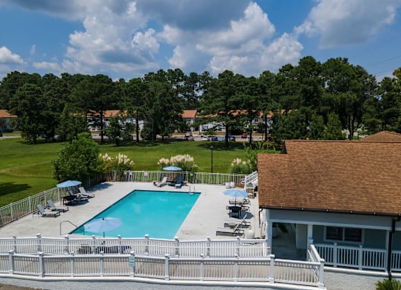 A pool surrounded by a white fence with trees in the background at Retreat at Savannah Apartments, Savannah, Georgia