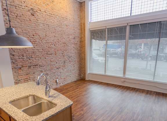 A kitchen with a brick wall and wooden floors.