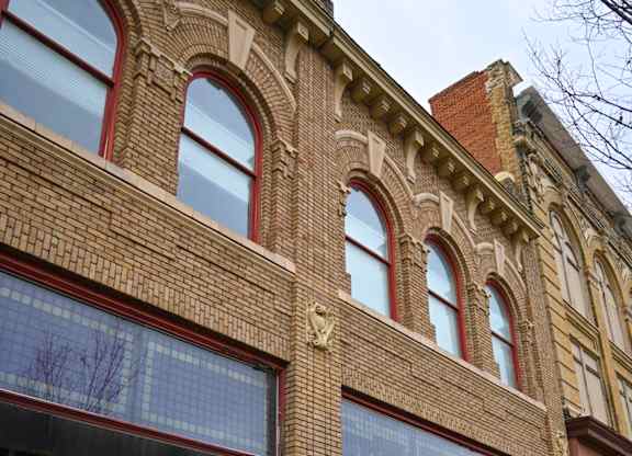 A red brick building with arched windows and a black awning.