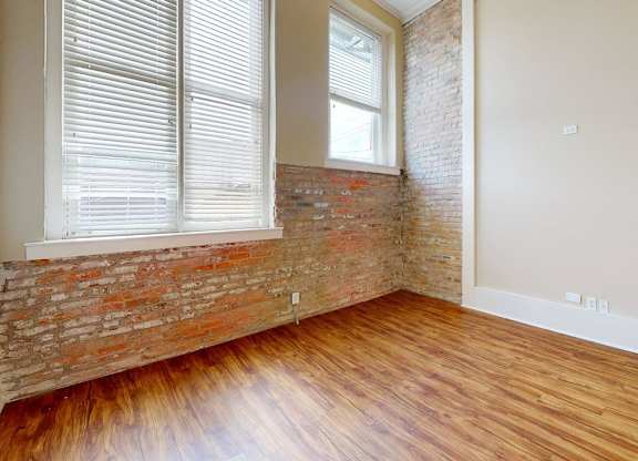 A room with a brick wall and wooden flooring.