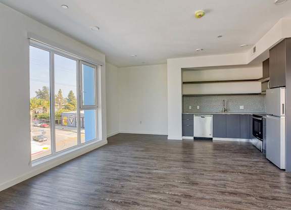 A spacious kitchen with a refrigerator, cabinets, and a countertop.at Catalina West Adams, Los Angeles California