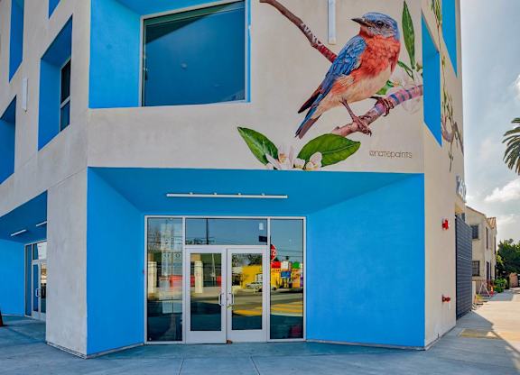 A blue building with a mural of a bird on it.at Catalina West Adams, Los Angeles, 90016