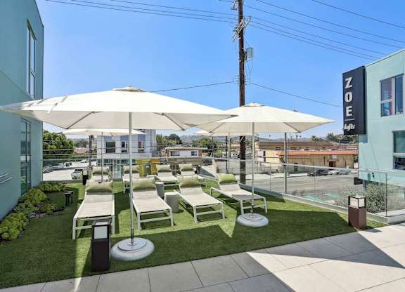 A patio area with white umbrellas and chairs.at Zoe Lofts, Los Angeles