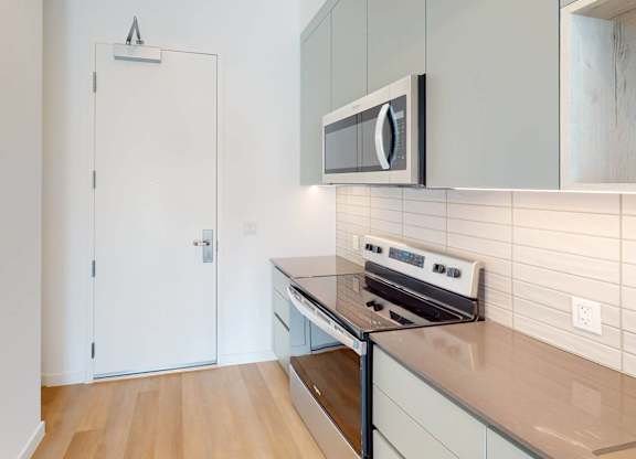 A kitchen with a stove, microwave, and cabinets.at The Dillon II at Silver Lake, Los Angeles California