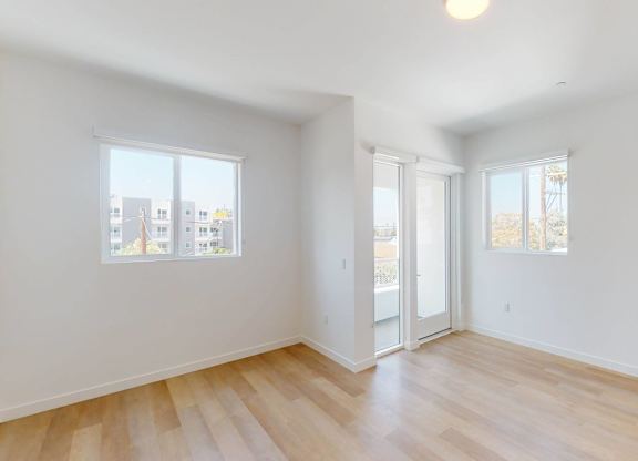 A room with wooden floors and white walls, with a ceiling light and two windows.at The Dillon II at Silver Lake, Los Angeles, CA