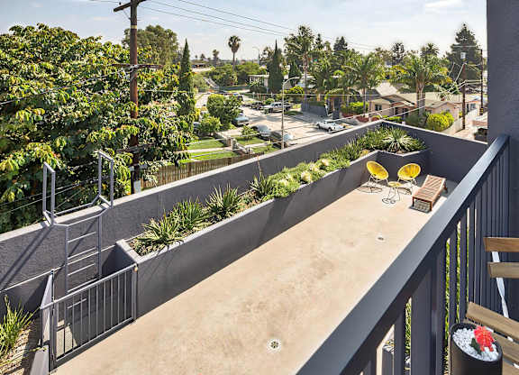 A balcony with a table and chairs overlooking a street.at 5135 W Adams, Los Angeles, CA