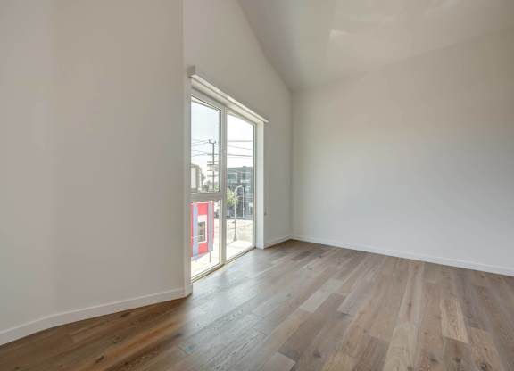 A room with wooden flooring and a large window.at 5263 W Adams, Los Angeles, 90016