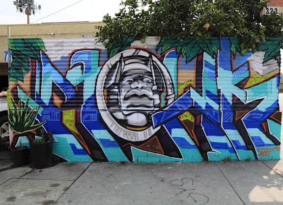 A mural of a man's face with a helmet on his head is painted on a wall.at 5263 W Adams, California, 90016