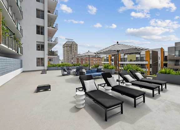A rooftop patio with black lounge chairs and a white table.