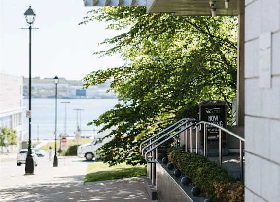 A white building with a black lamp post on the left and a tree in front of it.