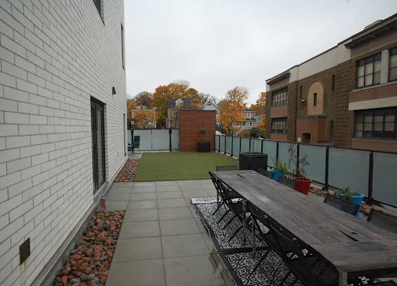 A white brick building with a long wooden table and chairs outside.