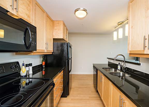 A kitchen with black countertops and wooden cabinets.